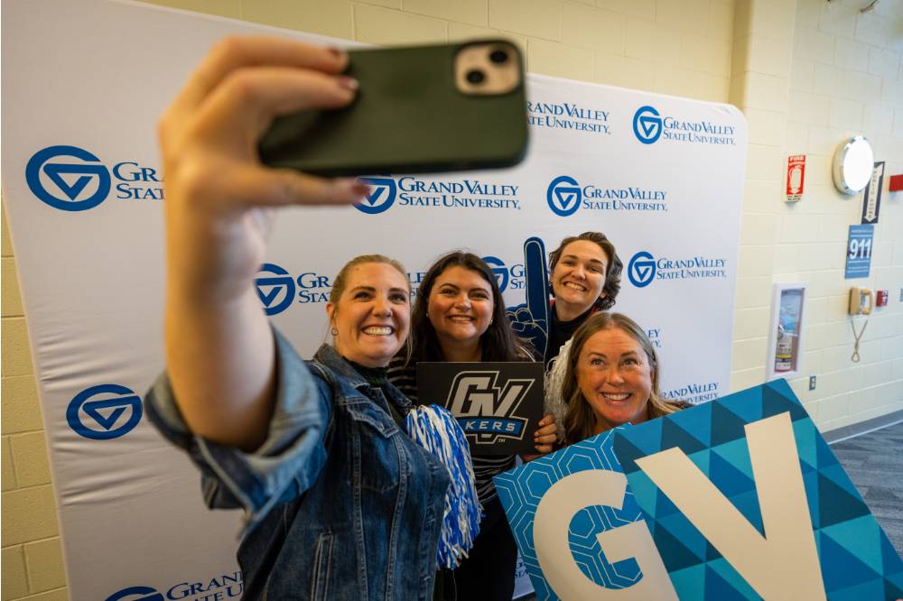 Group photo: someone taking a selfie, the group posing with foam fingers and the GV signs